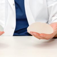 Doctor holding silicone implants for breast augmentation, space for text. Plastic surgeon hands holding silicon breast implants. Cosmetic surgery.